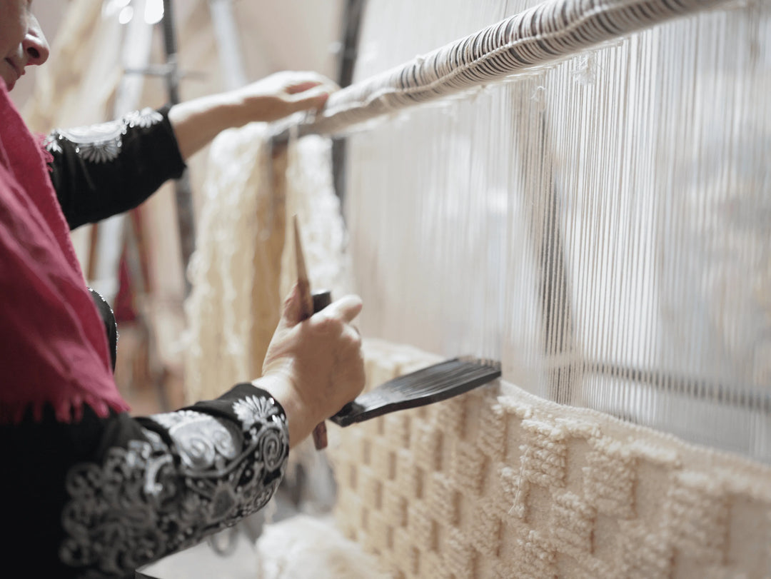 A Berber artisan handmaking a cream rug on an ancient machine