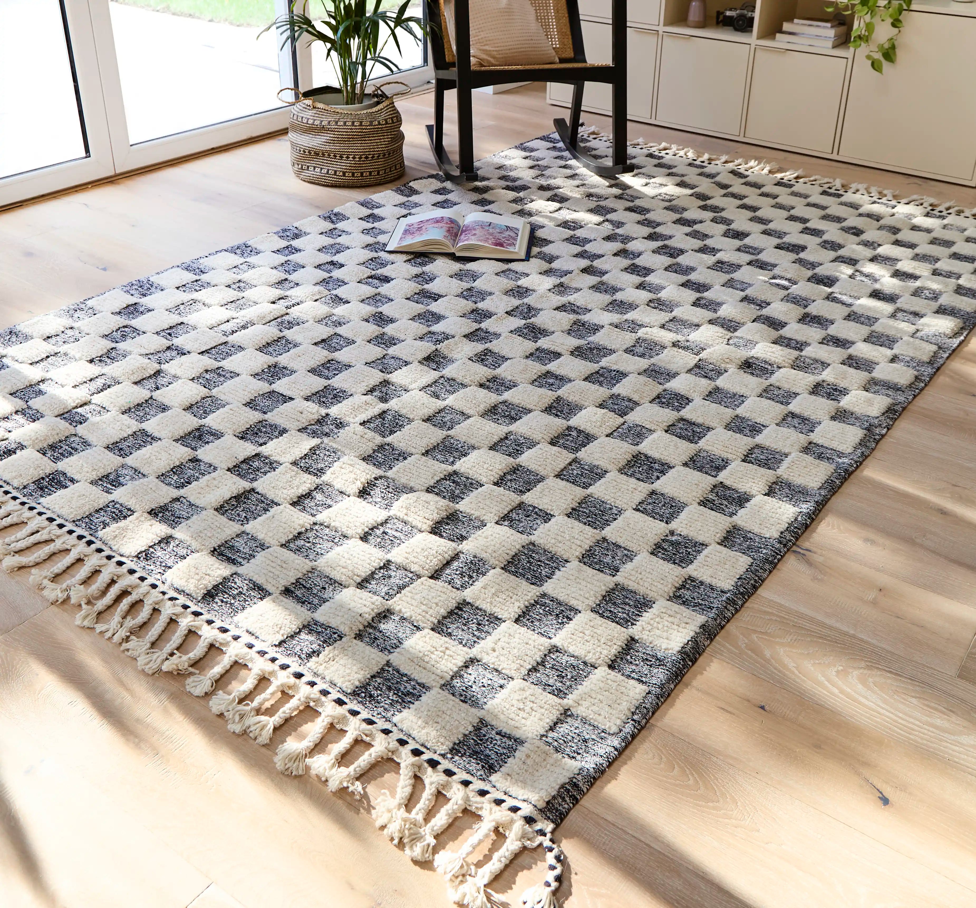 Black and white checkered Berber rug on a wooden floor in a sunlit room