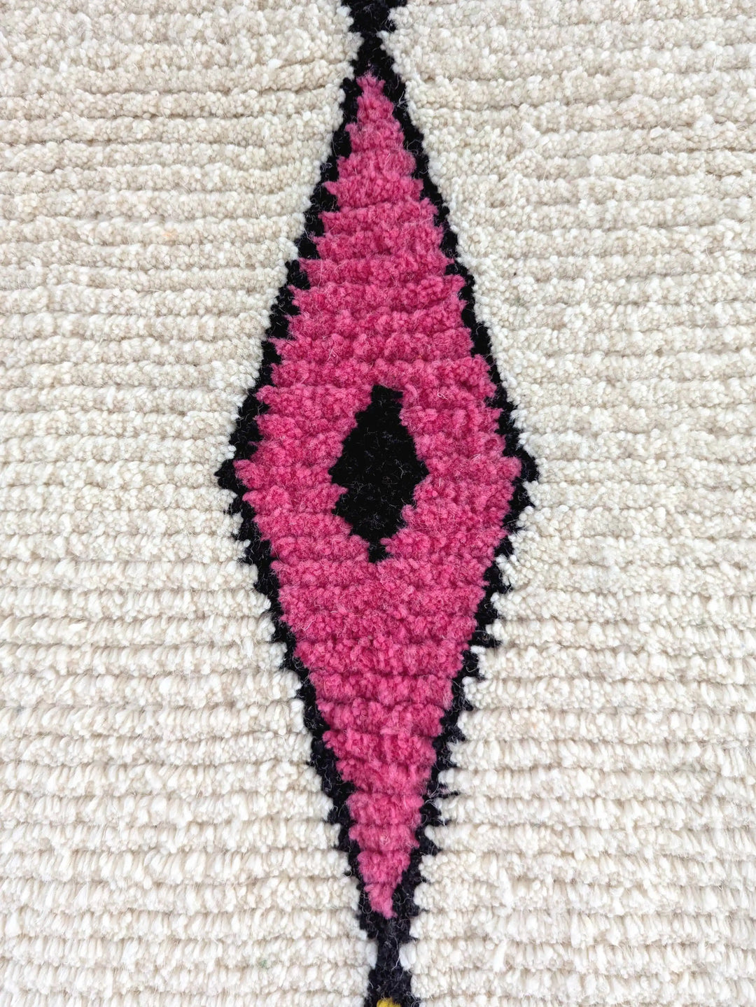 A close up of a pink diamond on a handmade berber wool rug
