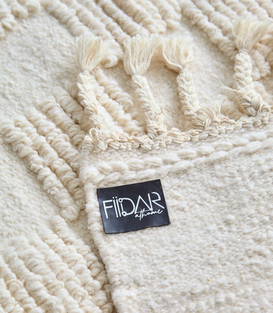 ​Back of handwoven cream Berber rug with square geometric design showing FiiDar logo. 